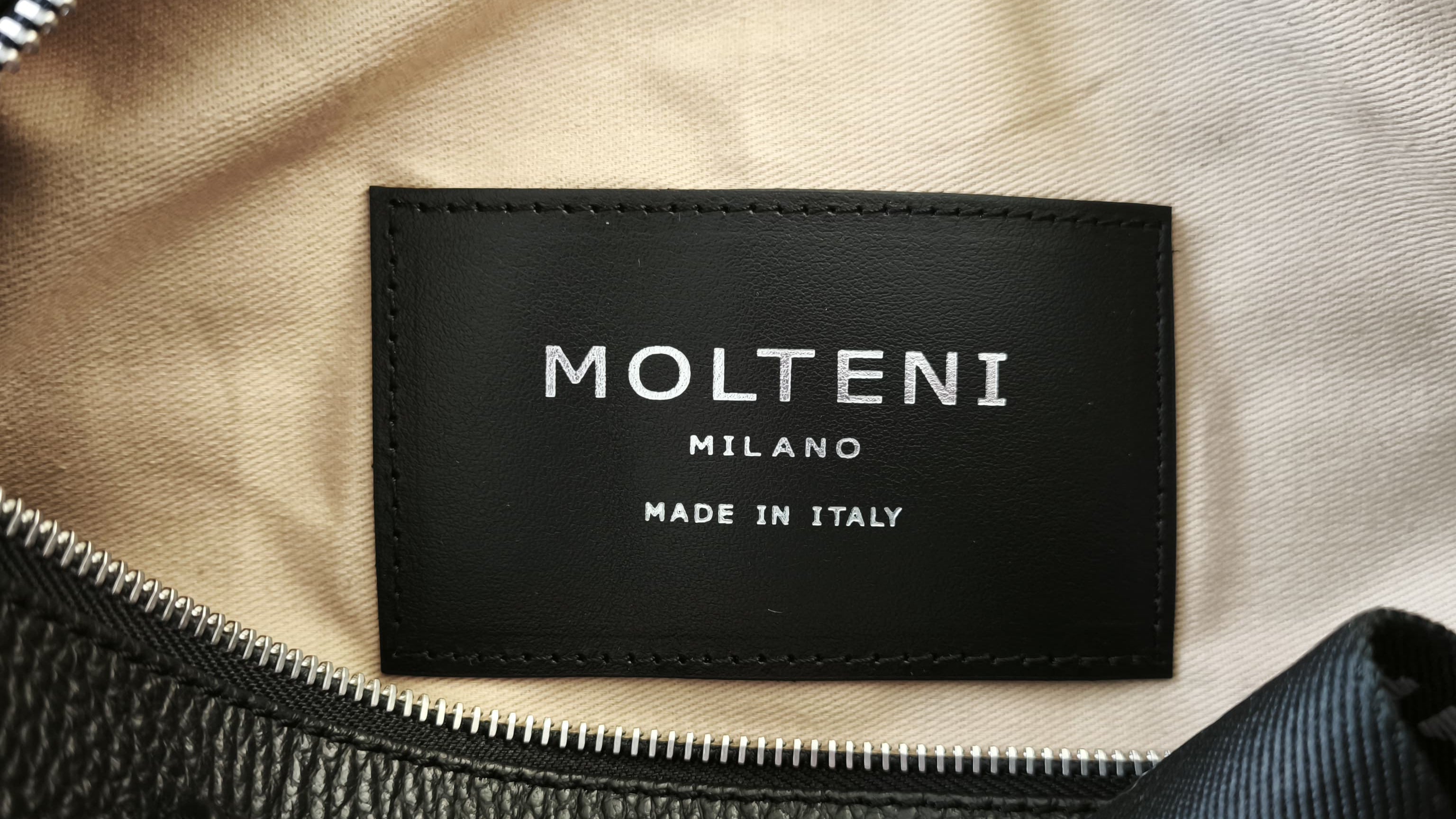 Targhetta interna riportante il logo MOLTENI MILANO e la produzione delle borse italiana, made in italy